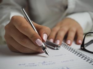 Woman in white shirt writing her to-do list